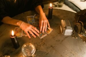 A fortune teller uses tarot cards and candles in a mystical indoor setting.